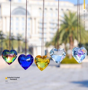 Detail of five multi-faceted heart-shaped crystal suncatchers in various colors hanging outdoors