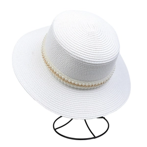 Detailed close-up of white straw hat featuring elegant faux pearl and gold chain band trim