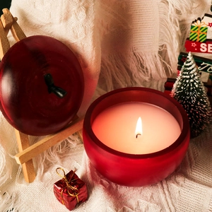 Bougie pomme rouge allumée sur couverture en maille blanche avec décor festif