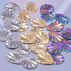 Gros plan de pendentifs en acier en forme de coquillage, finitions argent, or et arc-en-ciel