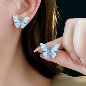 Détail macro de boucles d'oreilles papillon bleues avec zircons étincelants sur fond noir