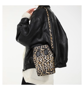 Detailed view of leopard print coffin-shaped crossbody bag worn with a black leather jacket