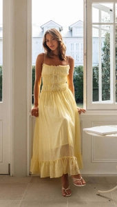 Détail d'une robe jaune midi avec tissu texturé, volants étagés et nœud papillon à la poitrine