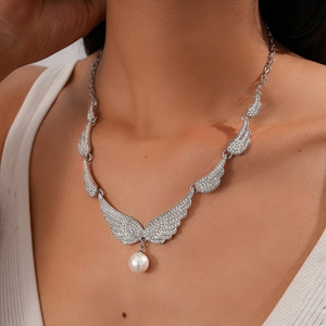 Detail of silver wing necklace with sparkling rhinestones and a white pearl pendant