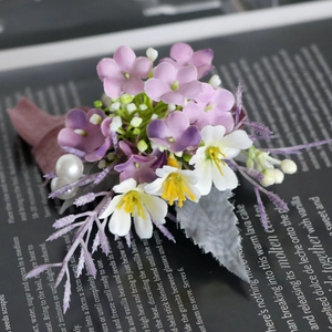 Elegant purple and white silk boutonniere with lavender and pearl detail on a book