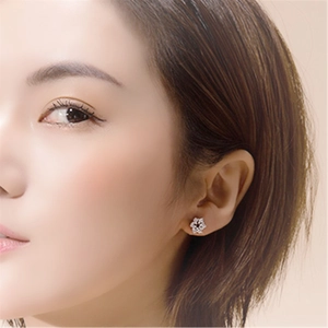 Macro shot of silver flower earrings with zircon inlays worn by a model