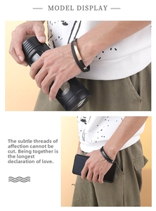 Detail view of a men's layered black braided leather bracelet with a gold metal plate detail