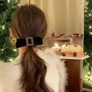 Détail d'une barrette à nœud en velours noir avec strass carré sur coiffure féminine