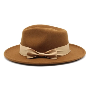 Detail of wool fedora hat with beige ribbon bow accent and textured felt finish