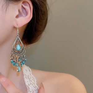 Macro view of vintage bohemian tassel earrings with sky blue rhinestones on model