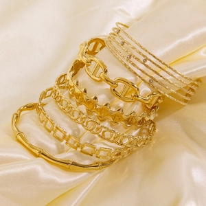 Set of 14K gold plated titanium steel bangles with bamboo and chain designs on silk fabric