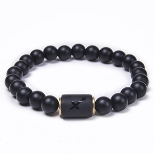 Macro view of matte black agate beads and Sagittarius zodiac metal charm bracelet