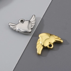 Detailed macro view of heart pendants with angel wings in polished gold and silver finish