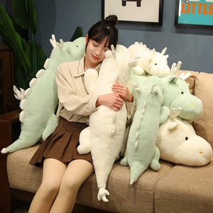 Detailed view of long soft plush white dragon and green dinosaur pillows on sofa