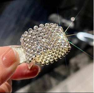 Close-up of golden alloy claw clip with sparkling rhinestones in a square design