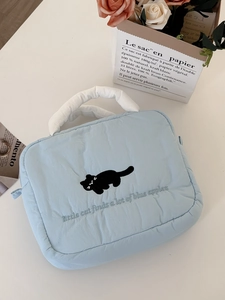 Macro view of light blue quilted cosmetic bag with cute cat embroidery and white handle