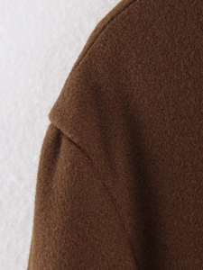 Macro view of dark brown wool coat stitching details and thick plush material texture