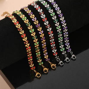 Detail view of gold and silver olive leaf bracelets with colorful enamel on black velvet
