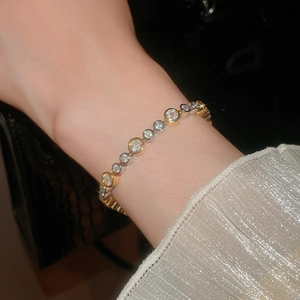 Close-up of gold and silver circle bracelet with inlaid zircons worn on wrist