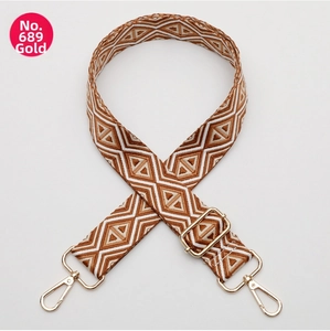 Detail of adjustable woven bag strap with golden hardware and brown geometric patterns