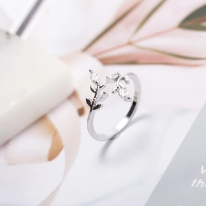 Leaf design zircon silver open ring displayed on a modern marble and pink leaf background