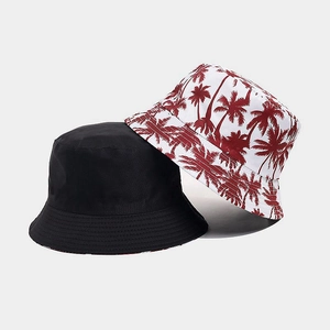Detail view of double-sided bucket hats in solid black and white coconut tree print