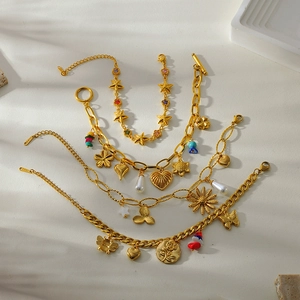 18K gold plated stainless steel bracelet with floral and heart charms on a stone surface