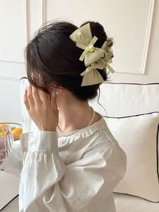 Detail of a light green silk bow hair clip worn by a model in a soft home setting