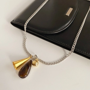 Detail of silver Cuban chain with gold trumpet, sphere and brown teardrop pendants