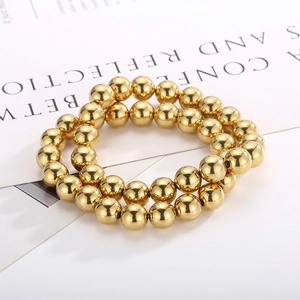 Detail view of two shiny gold-plated elastic bead bracelets with metallic luster
