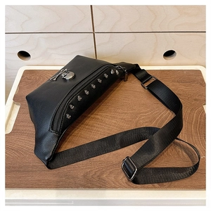 Detail of black leather chest bag with silver skull motif and studded zipper