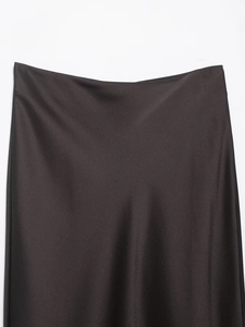 Détail de la jupe en satin marron foncé montrant la texture brillante et la coupe de taille