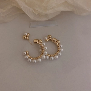 Detail of vintage C-shaped gold hoop earrings with inlaid white pearls on fabric