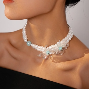 Close-up of double-layer necklace with white faux pearls and clear glass flower pendants