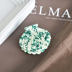 Macro view of shell-shaped acetate hair claw clip with vintage floral pattern