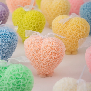 Detailed view of heart-shaped rose candles in pastel colors with silk bow ribbons