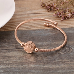 Detail of rose gold cable twist cuff bracelet featuring a cute pet paw print charm