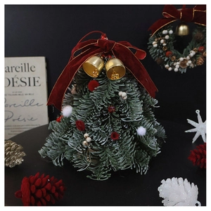 Close-up of mini Christmas tree with red velvet bow, gold bells and white-red ornaments