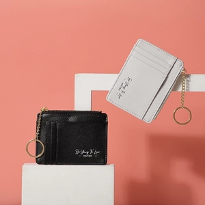 Detail of mini faux leather card holders in black and beige with gold keychains