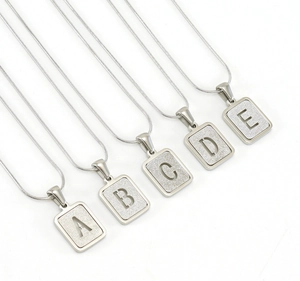 Vue détaillée de cinq pendentifs rectangulaires en acier doré 18 carats avec lettres sablées