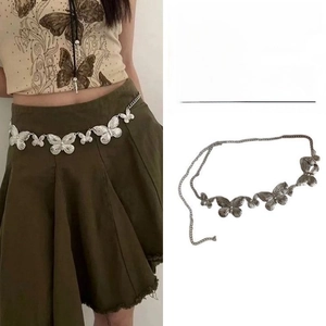 Detail of matte silver metal waist chain with butterfly links and dangling charms