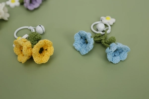 Close-up of handmade crochet lily of the valley keychains in yellow and blue colors