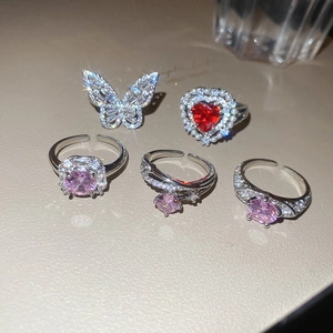 Detailed view of silver open rings with butterfly, heart, and pink zircon stones
