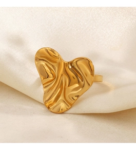 Detailed view of irregular gold heart ring on elegant beige silk background
