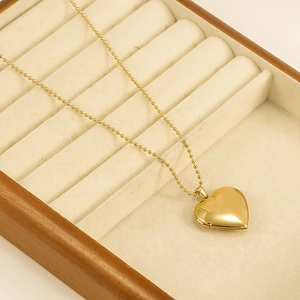 Golden heart locket necklace with bead chain displayed on a premium beige velvet jewelry box