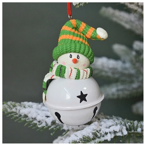 Detail of Christmas snowman bell ornament with knitted hat on snowy pine branch