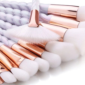 Detail of white synthetic fiber bristles and rose gold ferrules of makeup brush set