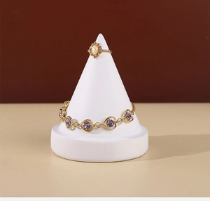 Detailed shot of gold heart bracelet with purple gems on white jewelry stand