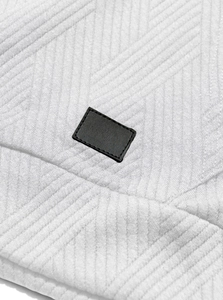 Detail of white textured fabric with a black leather patch on a hooded tank top