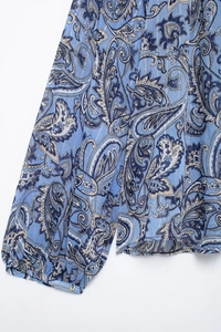 Dettaglio della camicia in chiffon blu paisley con polsini increspati a maniche lunghe